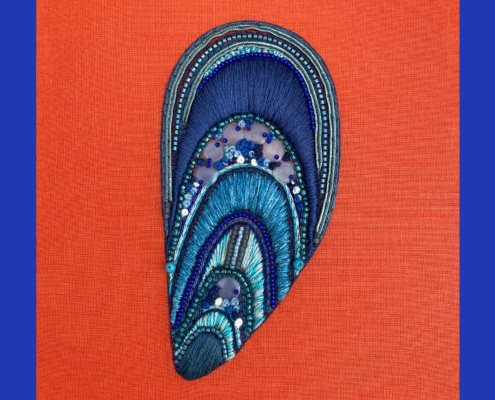 Broderie abstraite avec des perles bleues et bleu sarcelle sur un fond en tissu orange, mettant en valeur le style unique de Lorkabrode. Limbus Studio