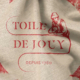 Tissu beige avec impression rouge indiquant "Toile de Jouy" et "Depuis 1760", avec un personnage dessinant au-dessus du texte. Parfait pour les amoureux de la tradition textile française et les fans du Musée de la Toile de Jouy. Limbus Studio