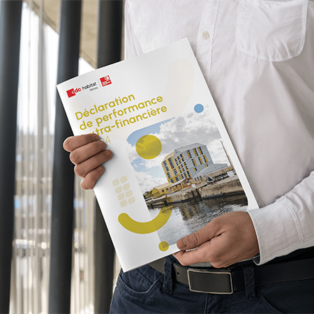 Une personne en chemise blanche tient un rapport d'activité de la CAMIEG de 2022 intitulé "Déclaration de Performance Extra-financière", avec un bâtiment sur la couverture. Limbus Studio